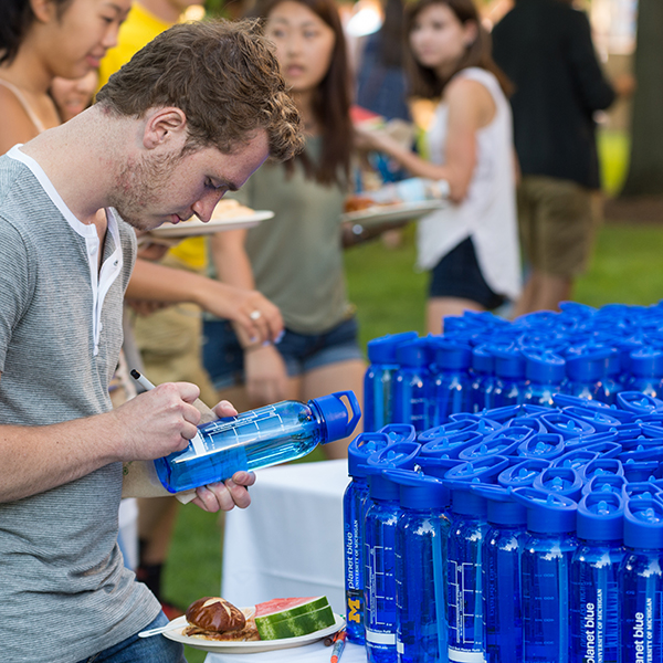 Student signing his University of Michigan water bottle